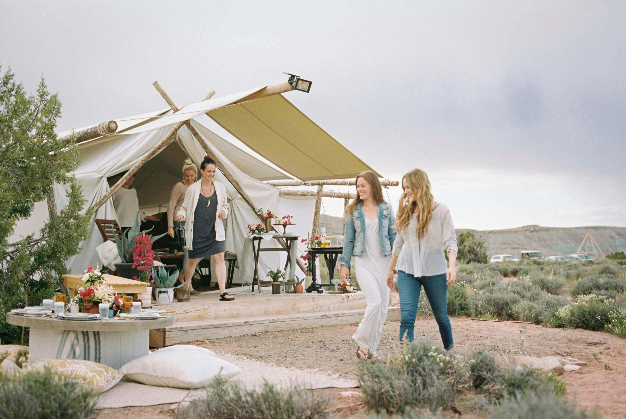 一群朋友享受户外用餐，背景帐篷。