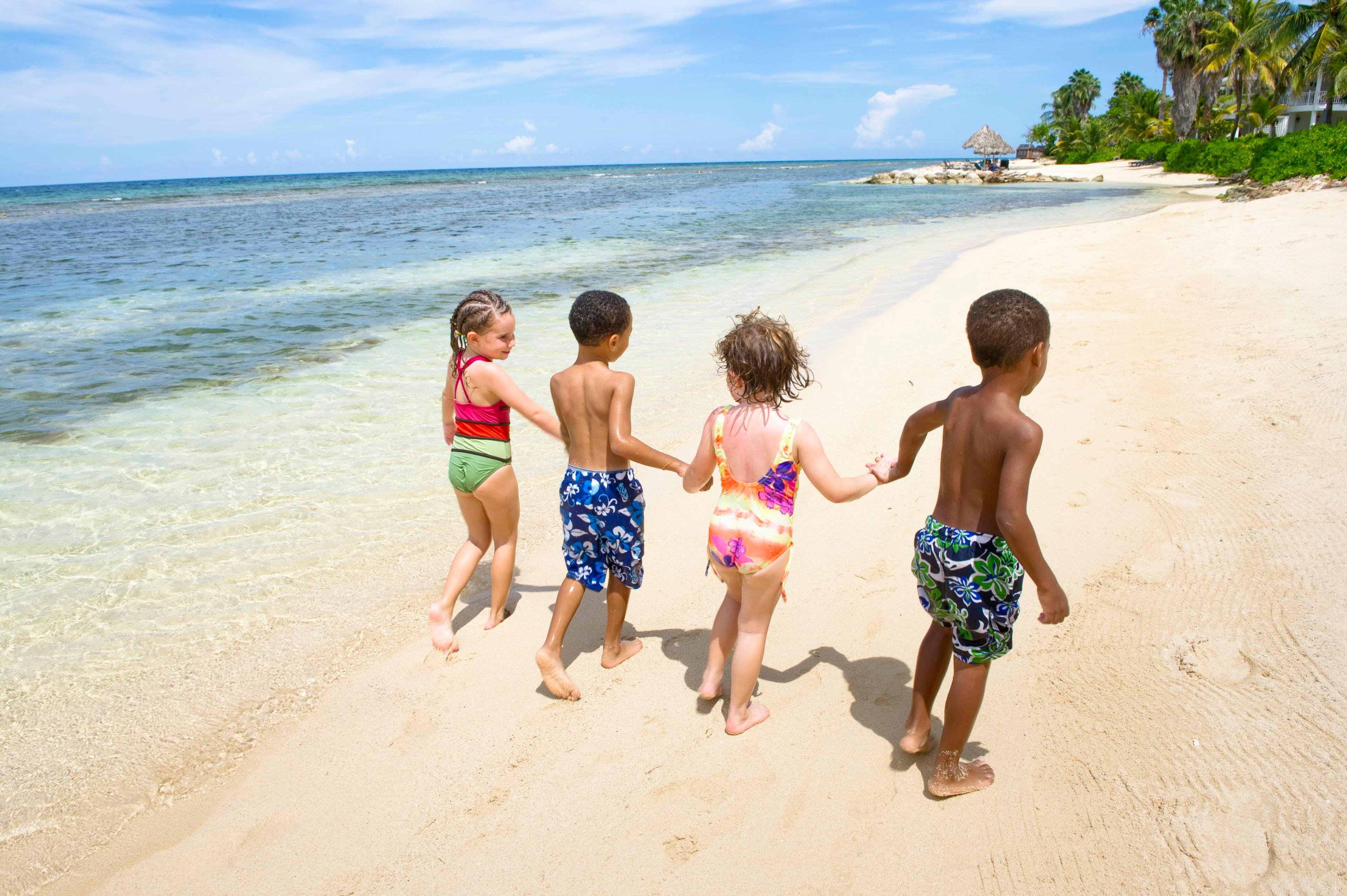 牙买加蒙特哥湾。黑白儿童在半月度假村海滩一起玩耍。